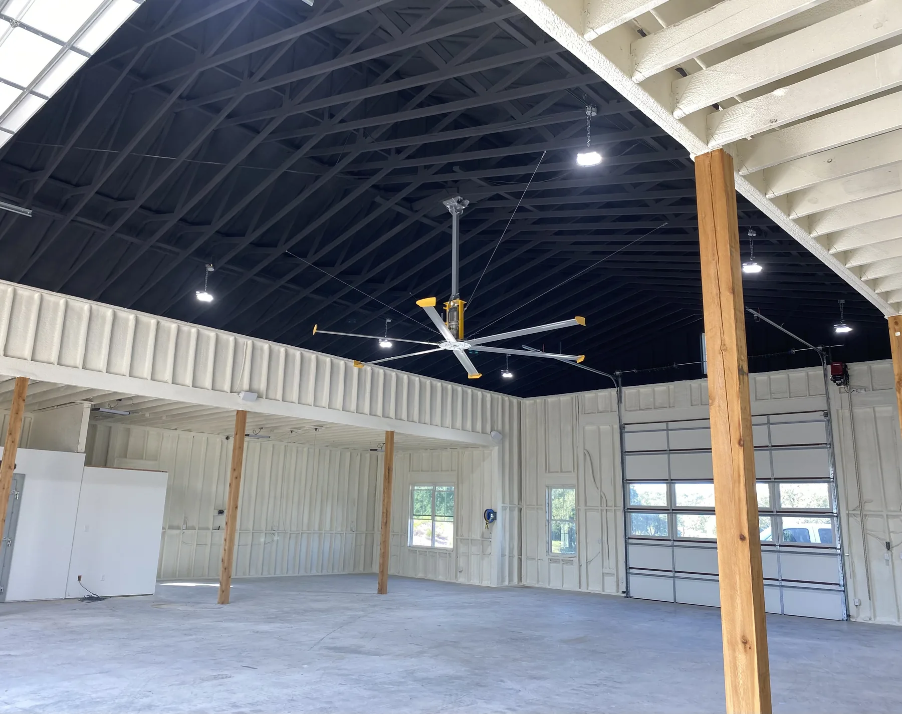 Shop interior showing white spray foam walls and painted dark roofline spray foam