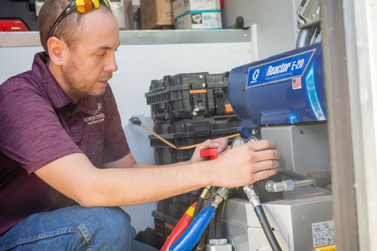 All Out Insulation technician checking spray foam rig controls
