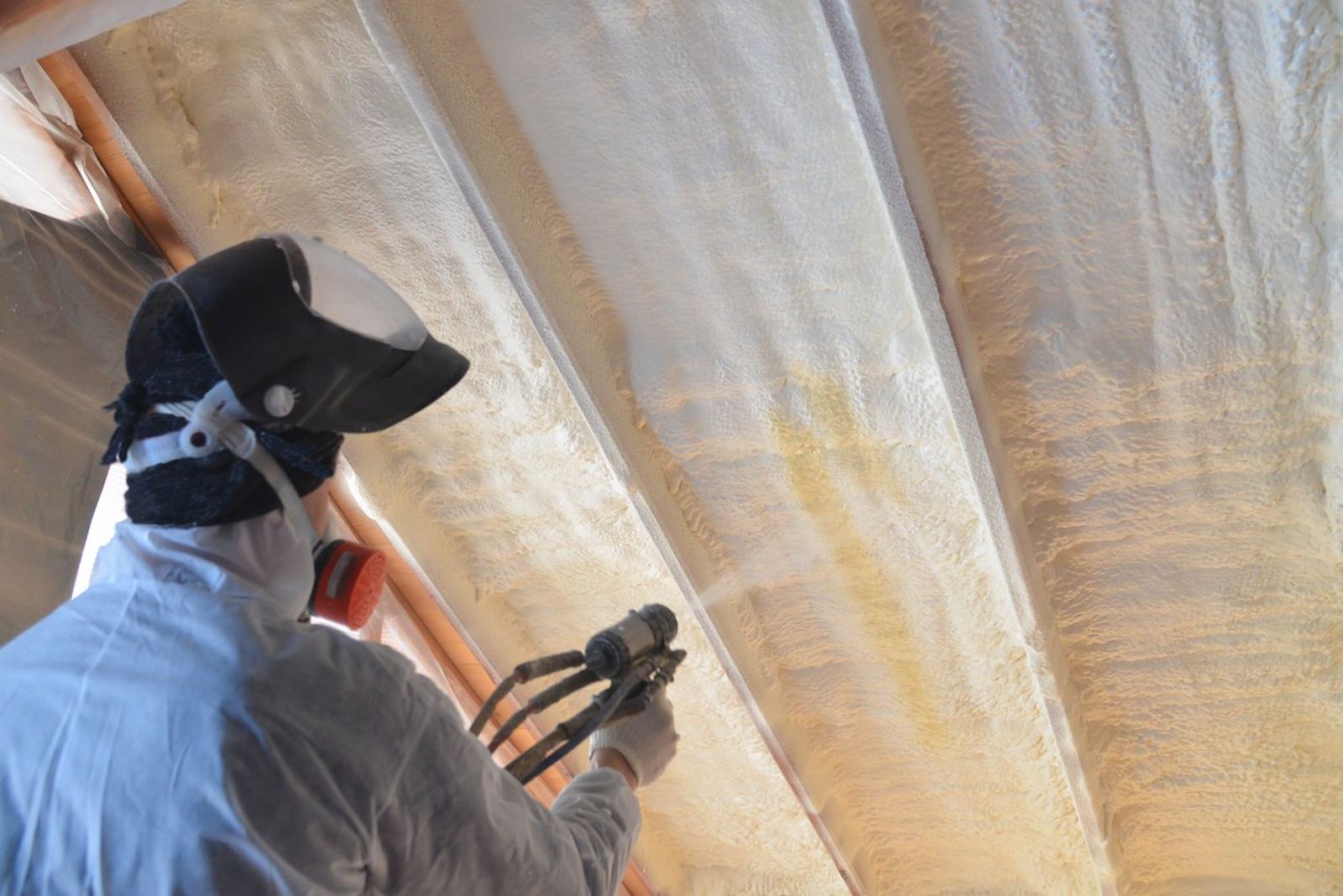 All Out Insulation technician applying closed-cell spray foam insulation to a roofline