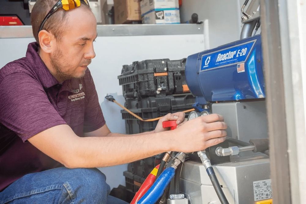 All Out Insulation technician calibrating a Graco Reactor E-20 spray foam rig